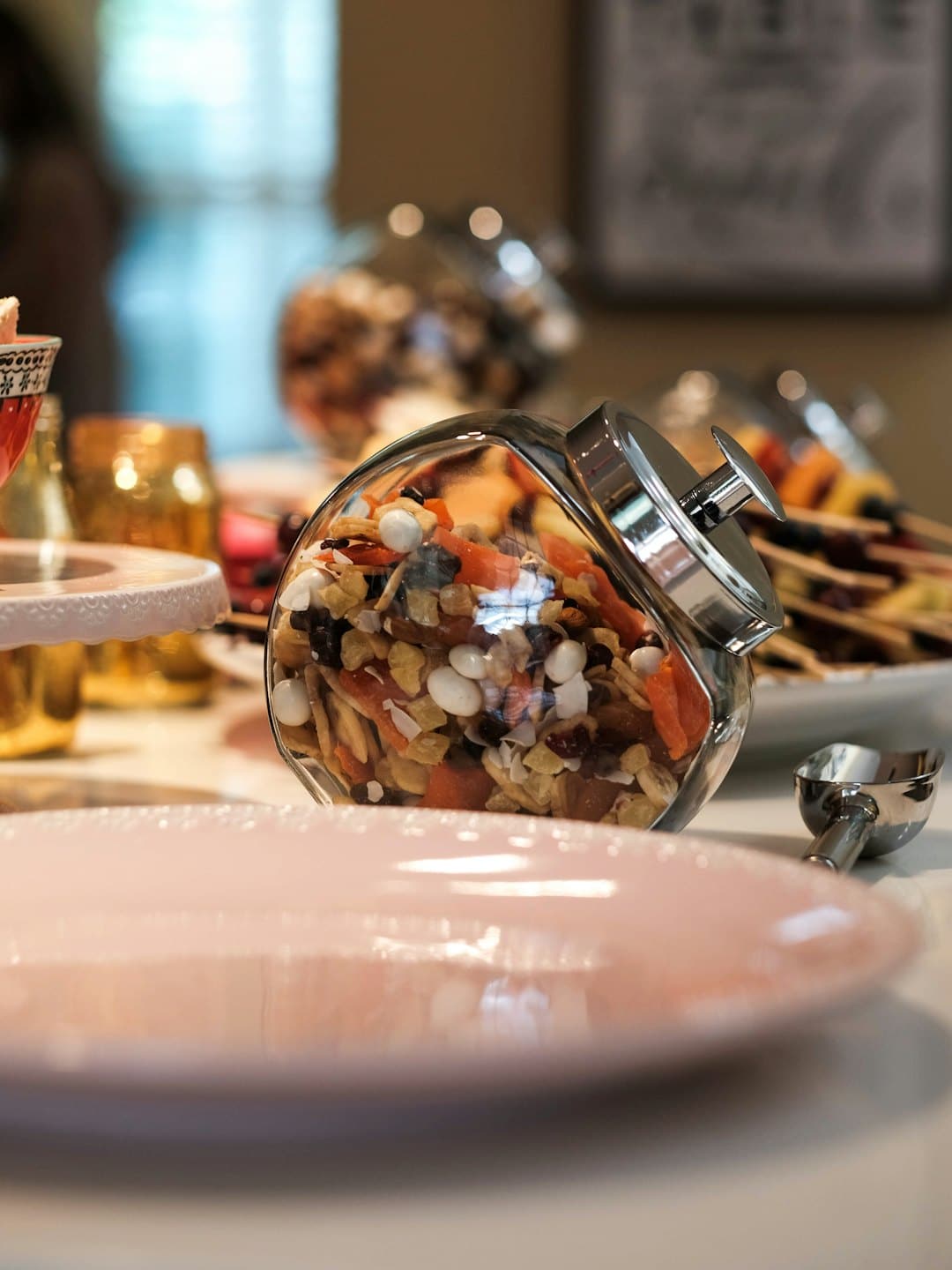 Glass jar filled with fruit and nut mix on a table.