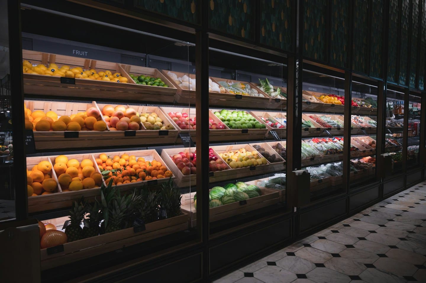 Wooden crates filled with fresh fruit and vegetables in supermarket display cases.